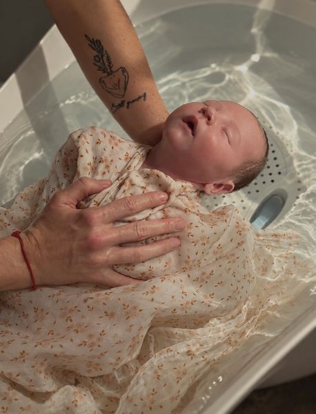 Bébé détendu dans un bain doux, tenu par des mains bienveillantes