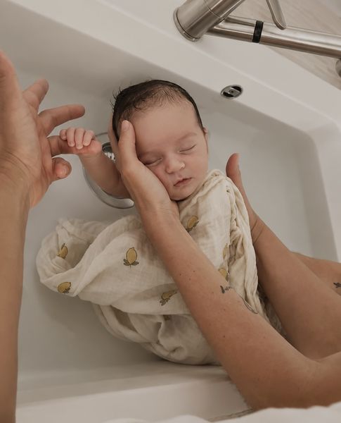 Bébé paisible dans l'eau tiède, soutenu avec douceur