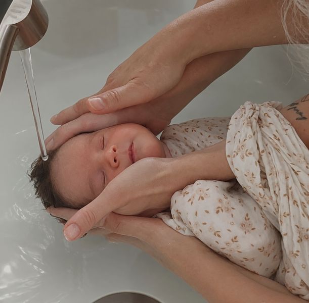 Tête de bébé délicatement rincée sous un filet d'eau tiède